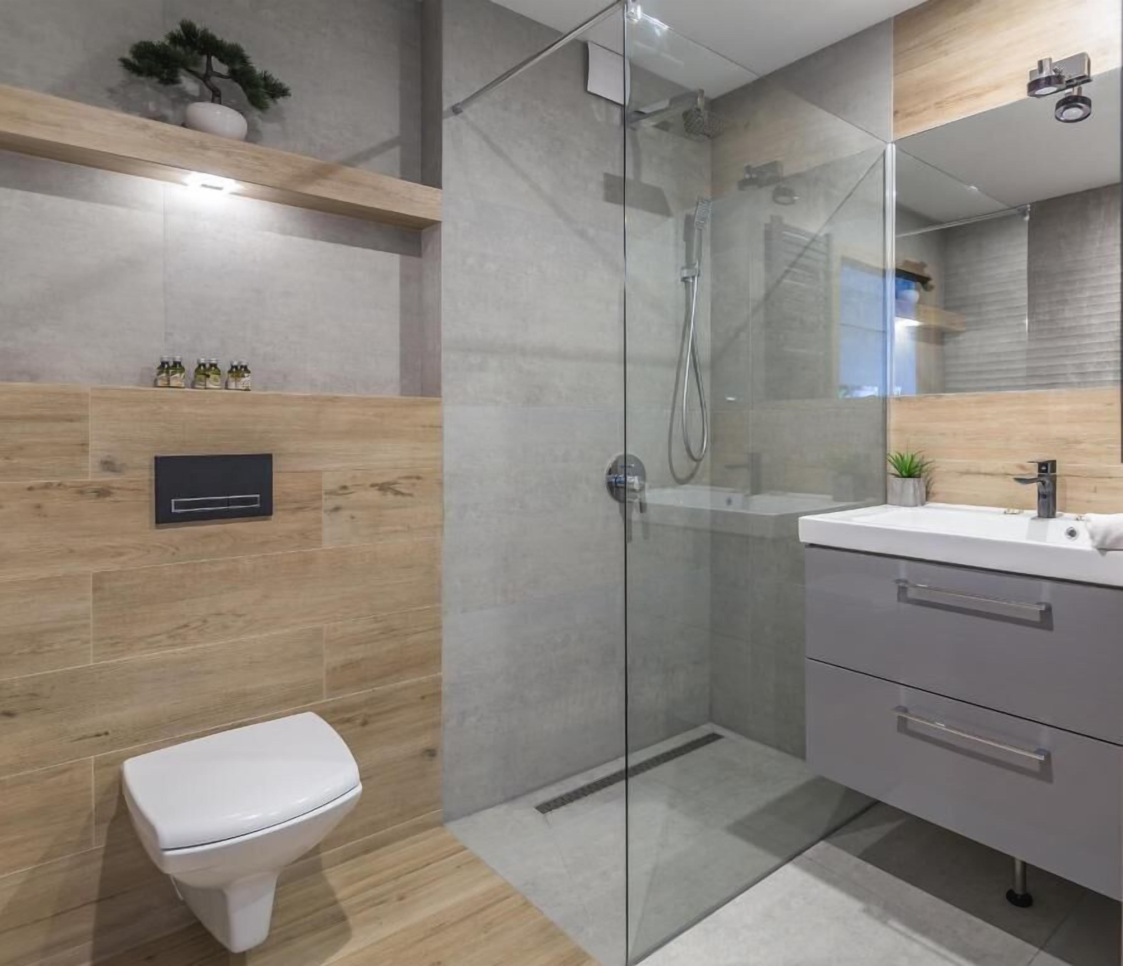A modern bathroom with a glass shower enclosure, a white toilet, and a vanity with a mirror.