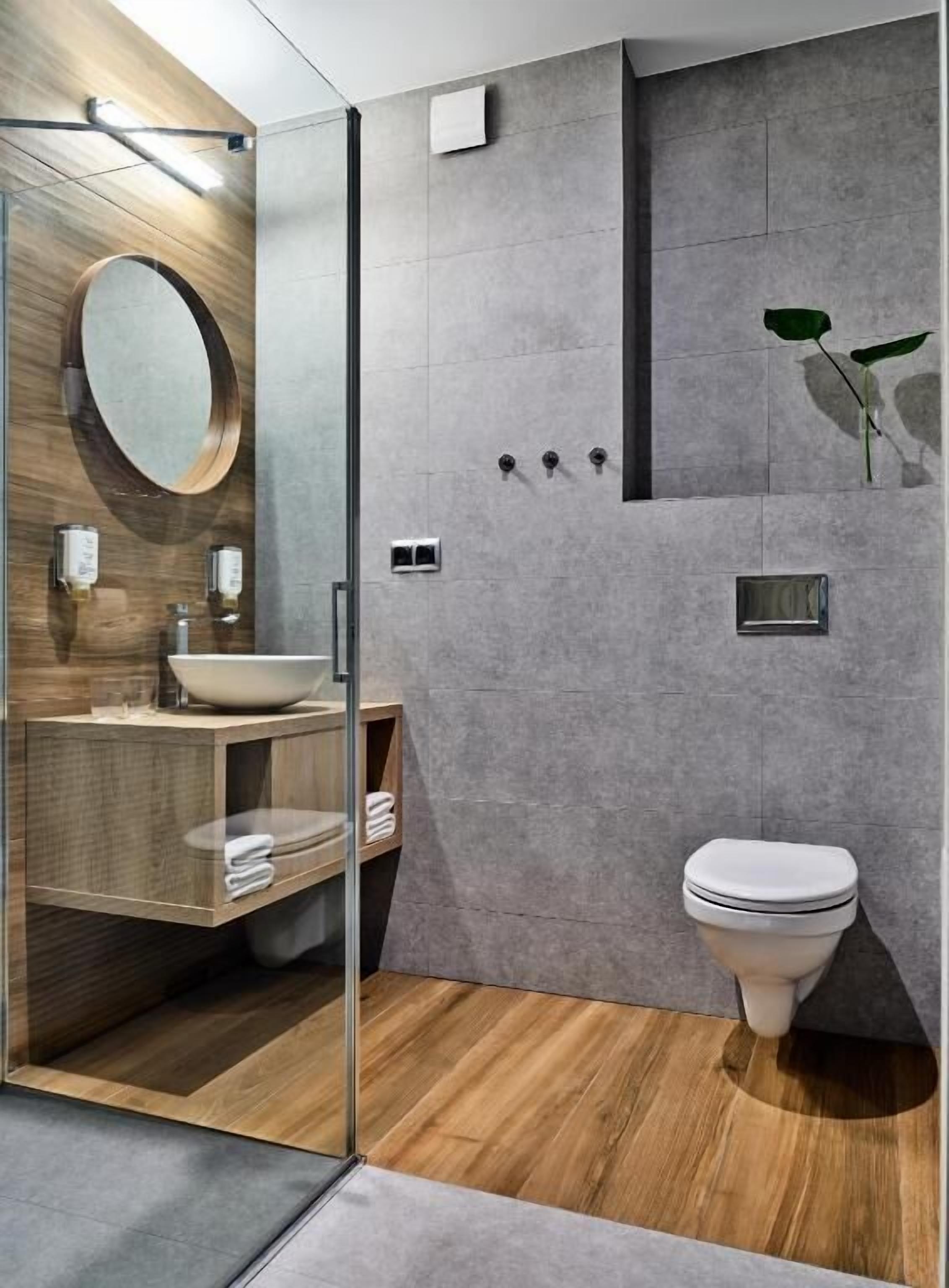 Een moderne badkamer met een douchecabine van glas, een houten wastafelmeubel, een grote spiegel en een toilet.