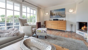 Un salon avec une cheminée, un canapé, une table basse et une grande fenêtre.
