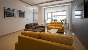 A modern living room with two sofas, a coffee table, and a flat-screen TV mounted on the wall. - STAY AT 9020 (St. Paul's Bay)