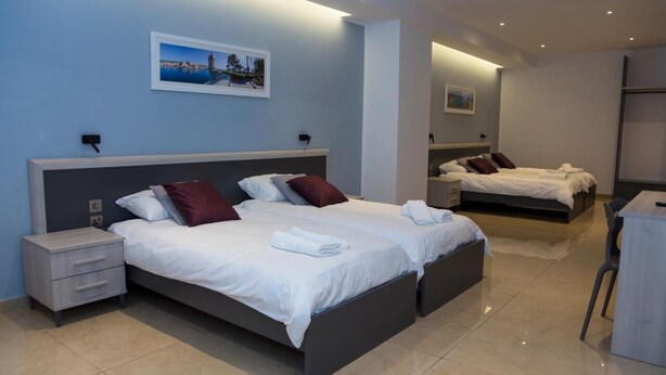 A modern hotel room with two beds, a desk, and a chair. - STAY AT 9020 (St. Paul's Bay)