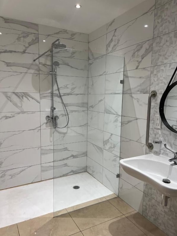 Un baño moderno con ducha, lavamanos y espejo.