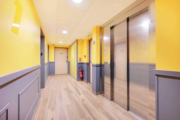 A hallway with yellow walls, grey and yellow trim, and wooden flooring.