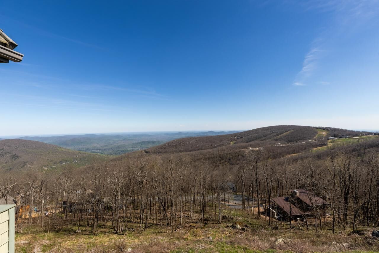 Eine gebirgige Landschaft mit einem Haus auf einem Hügel.