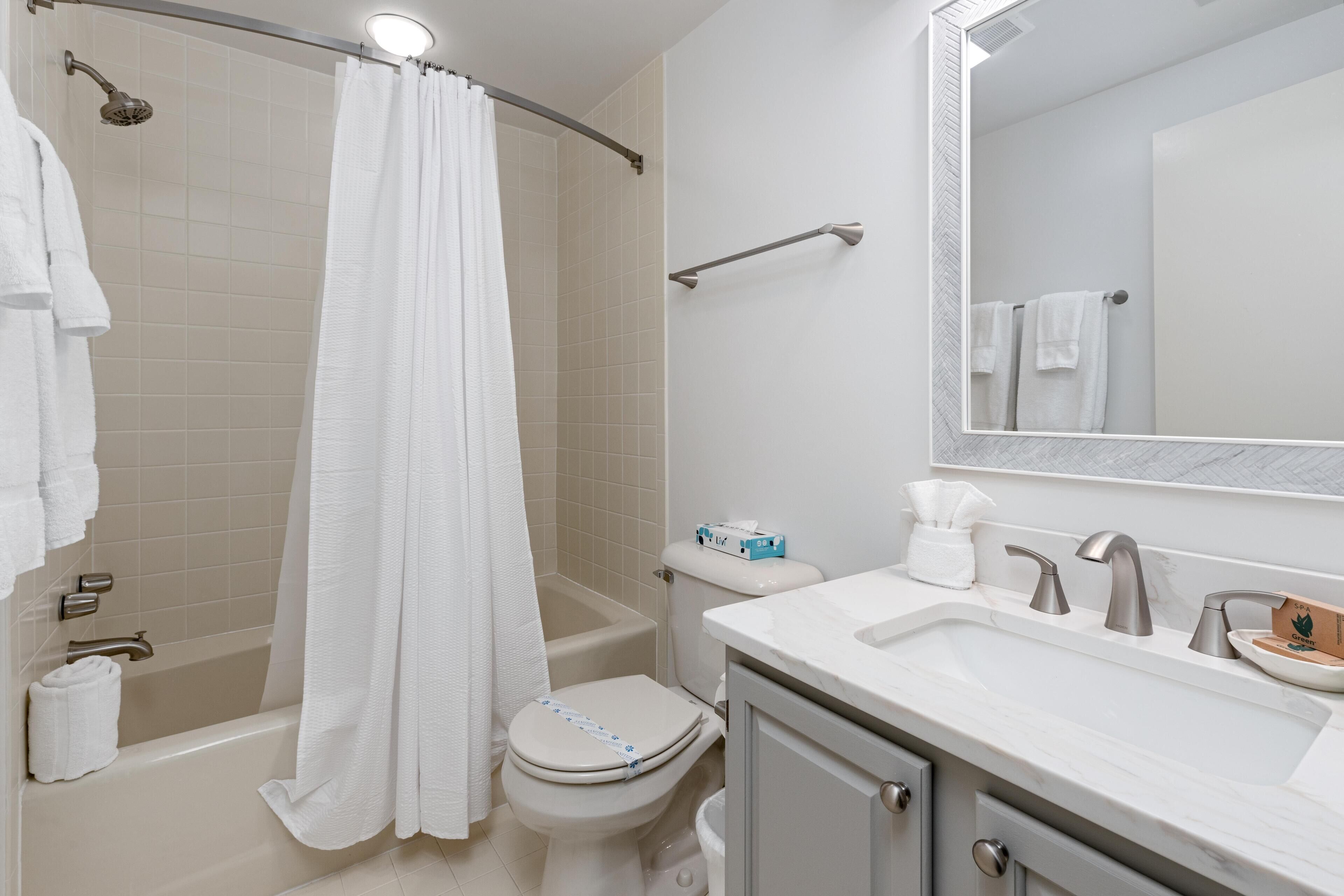 Une salle de bain équipée d’une douche, de toilettes, d’un lavabo et d’un miroir.