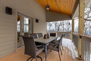 A covered outdoor patio with a table and chairs, a wooden deck, and a view of trees. - Antlers Aweigh with Wintergreen Advantage (Wintergreen)