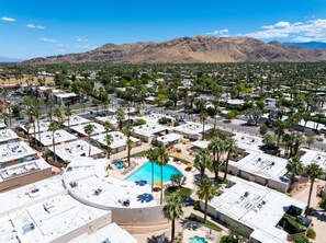 An aerial view of a resort with multiple buildings, a central swimming pool, and palm trees. - Desert Dream - OCotillo Lodge with Fitness Center (Palm Springs)