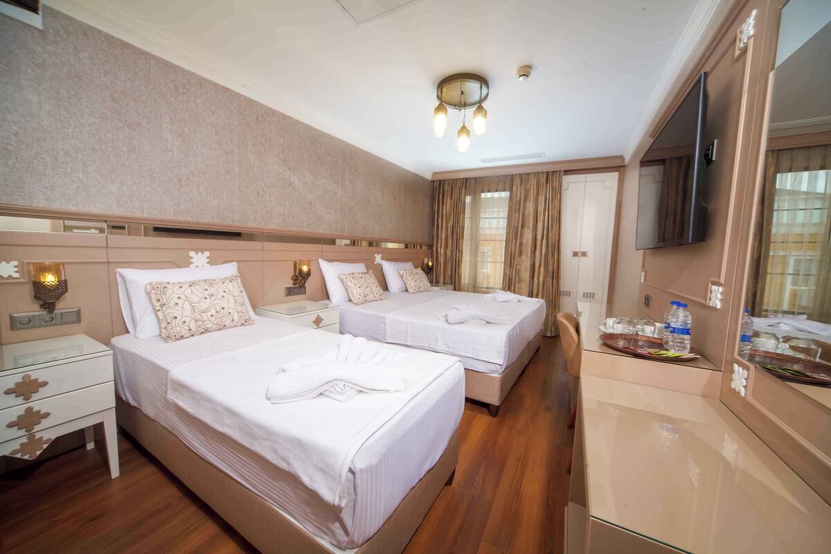 A hotel room with two beds, a TV, and a minibar.