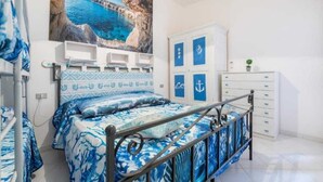 Un dormitorio con cama, armario, escritorio y estante en la pared.