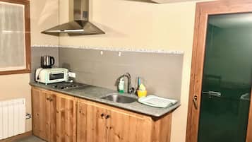 Una cocina con armarios de madera, campana extractora de acero inoxidable, un tostador, un fregadero y una ventana.