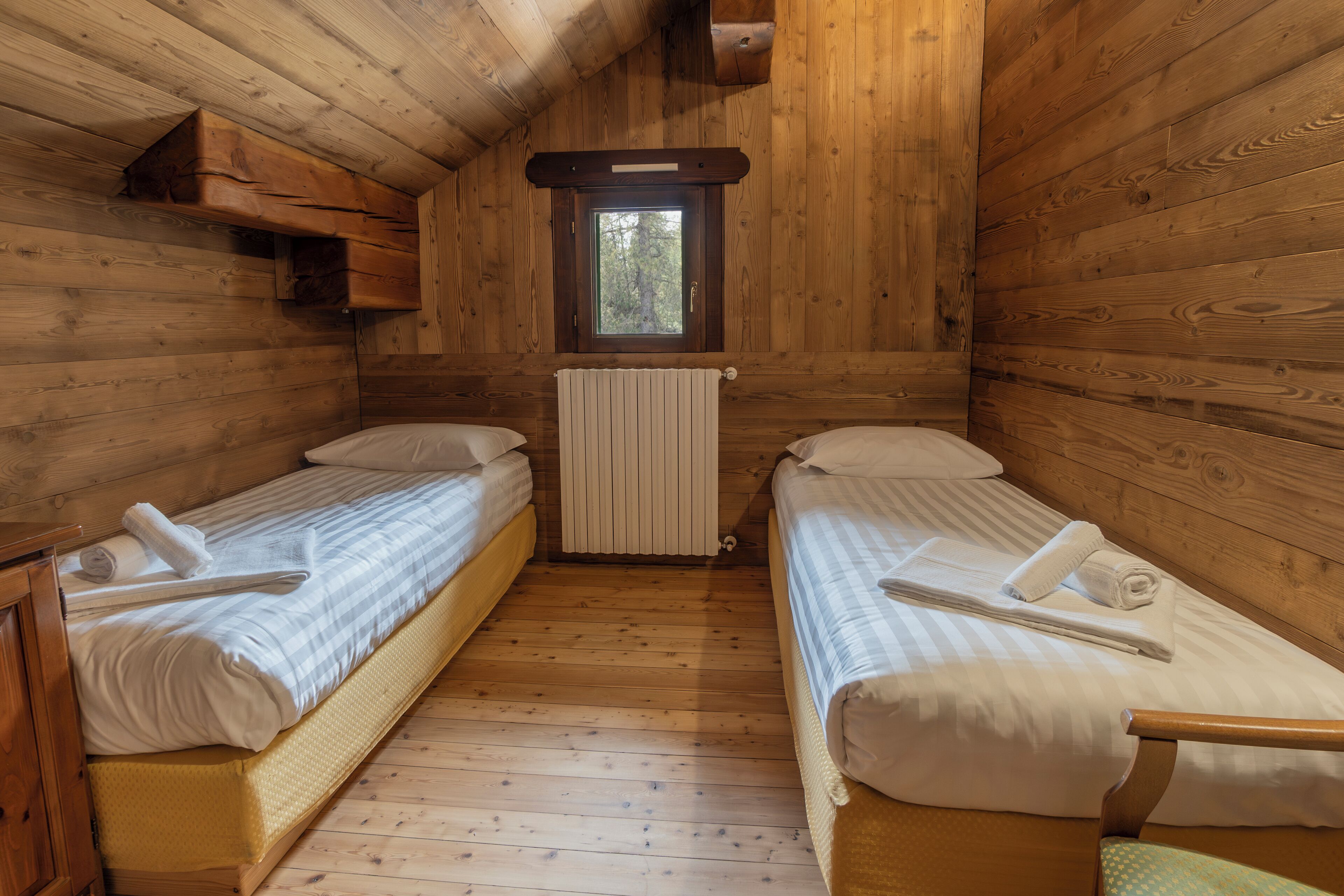 A cabin with two wooden bunk beds, a window, and a radiator.