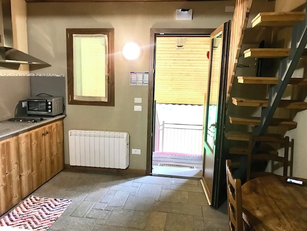 A compact kitchen with a built-in microwave, a white radiator, and a wooden counter. - Hotel Chamois d'Or (Tende)