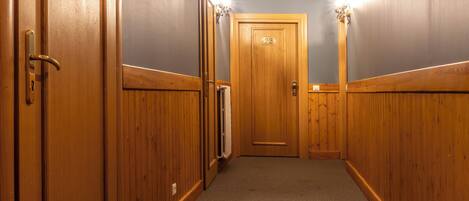 A hallway with wooden doors and a carpeted floor.