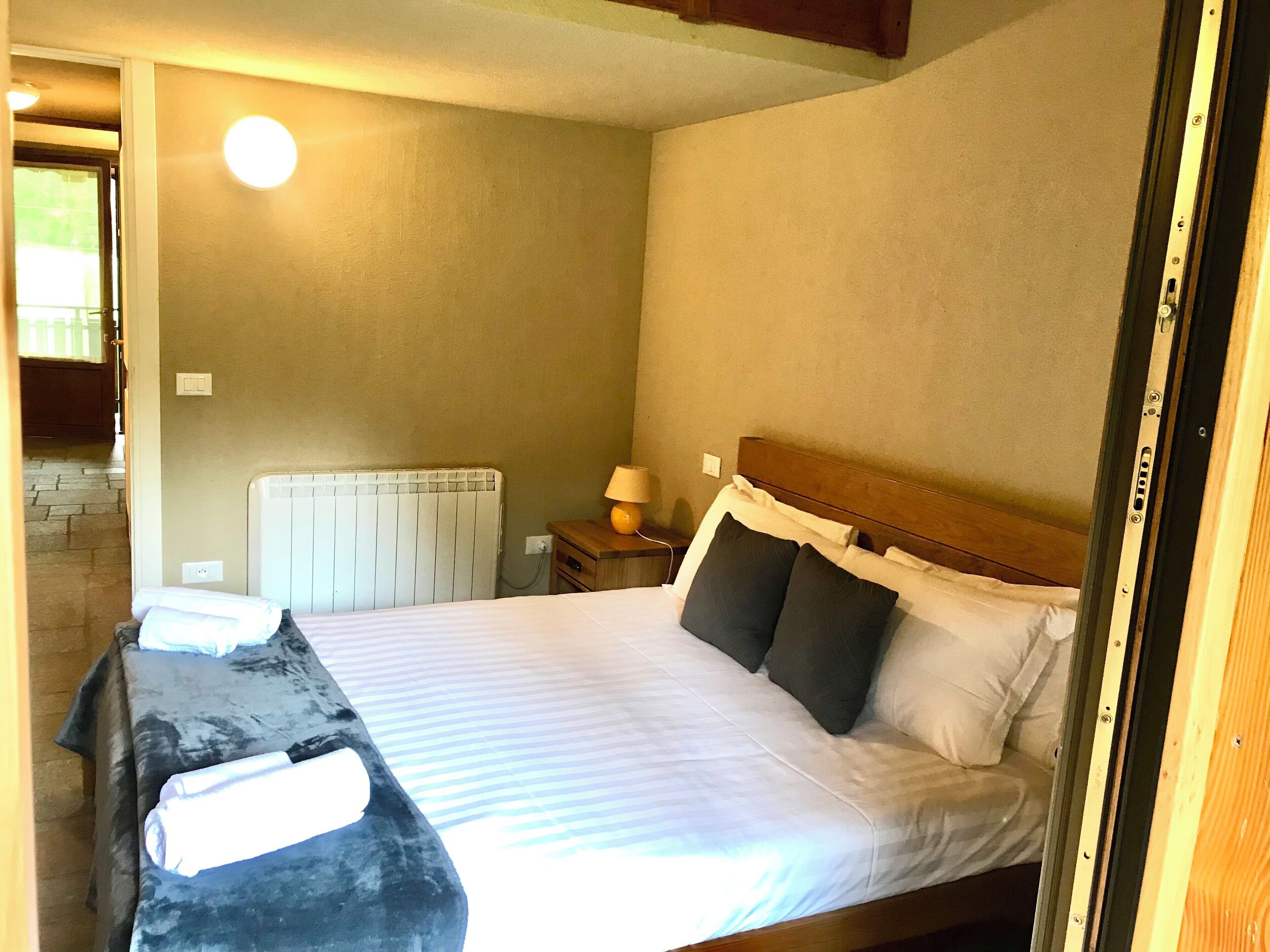 A bedroom with a bed, a bedside table, a lamp, and a radiator.
