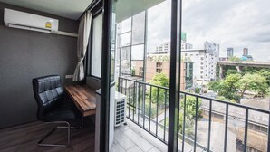 Een moderne kamer met een groot raam, een zwarte leren fauteuil, een houten tafel en een airconditioning.