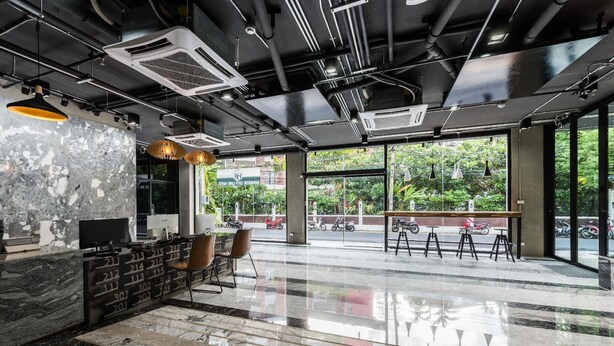 Een modern interieur met een marmeren receptiebalie, een zithoek en grote ramen met uitzicht op de straat.