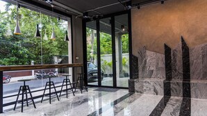 Een modern interieur met een glazen deur naar buiten, een marmeren vloer en een zithoek met krukken.