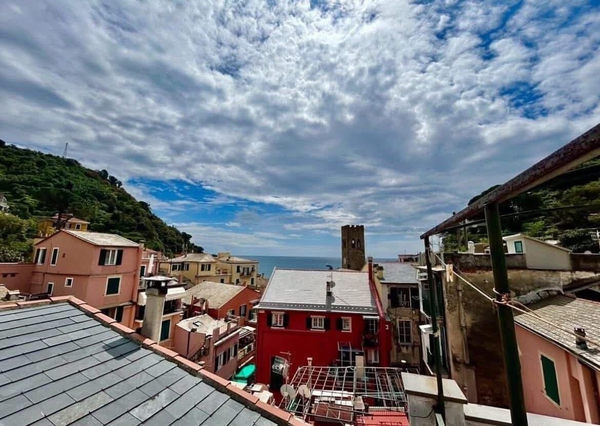 Uma vila costeira com edifícios, incluindo um prédio vermelho e uma torre.