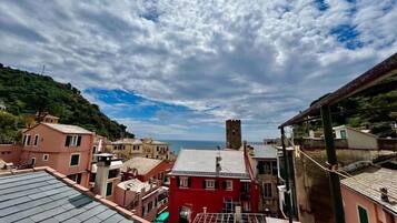 Uma vila costeira com edifícios, incluindo um prédio vermelho e uma torre.