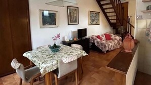 Un espace de vie compact comprenant un coin repas, un canapé, un téléviseur et un escalier.