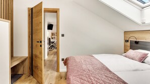 A bedroom with a sloped ceiling, a skylight, a bed with a pink quilt, and a wooden headboard. - Lux Apartment close to castle Podreda with balcony 2 unit (Šmarje pri Jelšah)