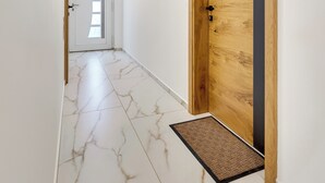 A hallway with a wooden door, a marble floor, and a doormat. - Lux Apartment close to castle Podreda with balcony 2 unit (Šmarje pri Jelšah)