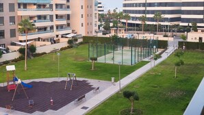 Ett bostadsområde med moderna lägenhetsbyggnader, en lekplats och en tennisbana.