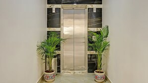 Un pasillo con piso de mármol, una puerta doble y dos macetas a cada lado.