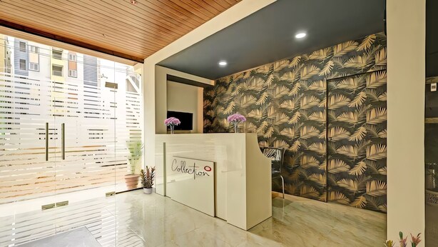 Un área de recepción con diseño moderno, que incluye un mostrador de recepción, un espejo grande y un muro con diseño.