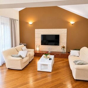 Una sala de estar con dos sofás, una mesa de centro y un televisor montado en una pared de madera.