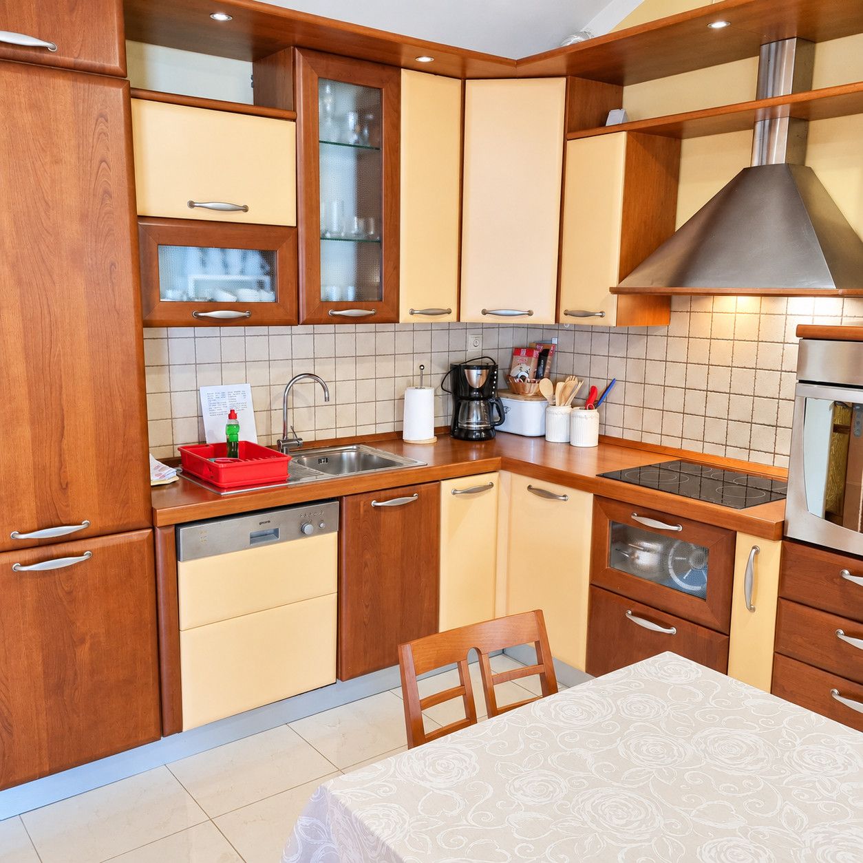 A compact kitchen with wooden cabinets, a built-in stove, and a dining area with a table.