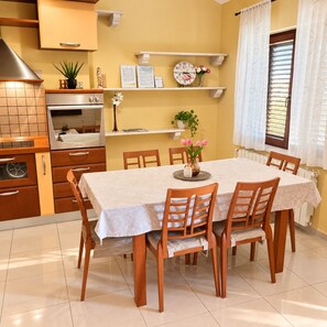 Comedor con una mesa dispuesta para seis personas, rodeado de sillas de madera.