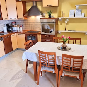 Cocina compacta con estufa, horno y comedor con mesa y sillas.