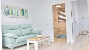 A modern living room with a light blue sofa, a wooden coffee table, and a painting on the wall. - El Rincon de Lidia . (Conil de la Frontera)