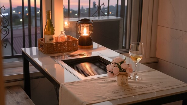 Une table avec une bouteille, une lanterne, un verre de vin et un panier de fleurs.