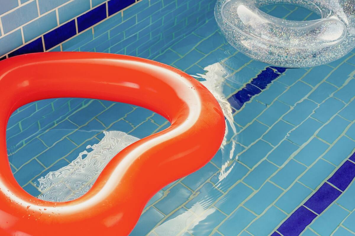 En swimmingpool med blå fliser og en rød oppustelig ring.