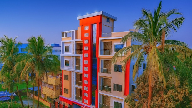 Un hôtel à plusieurs étages, à la façade rouge et blanche, entouré de palmiers.