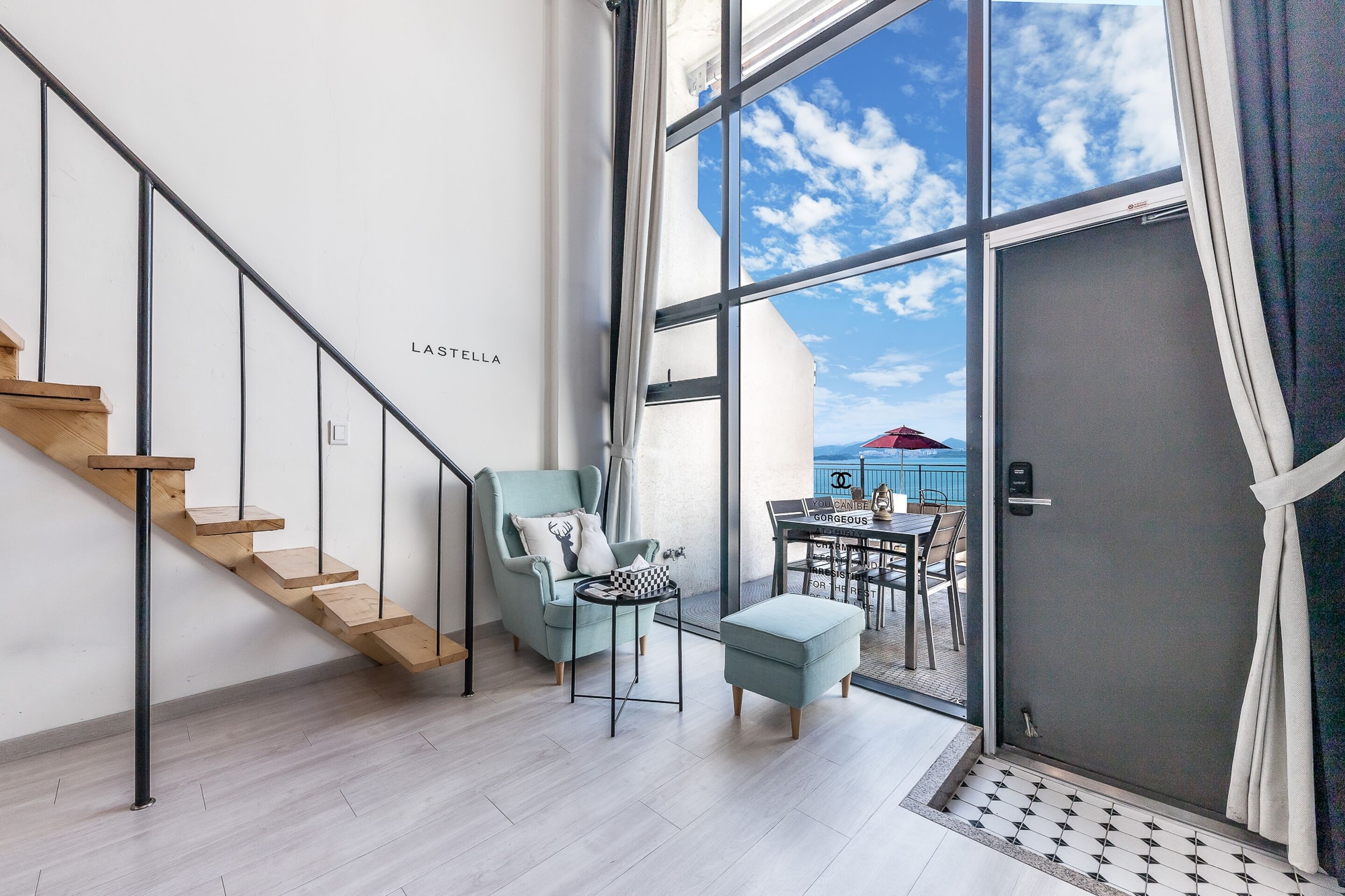 Un interior moderno con una escalera, una zona de estar con vistas y un ventanal grande.