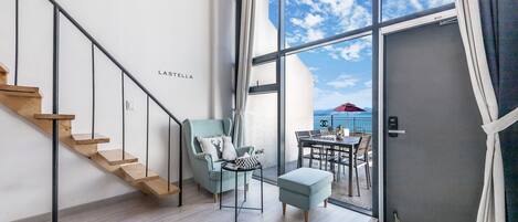 Un interior moderno con una escalera, una zona de estar con vistas y un ventanal grande.
