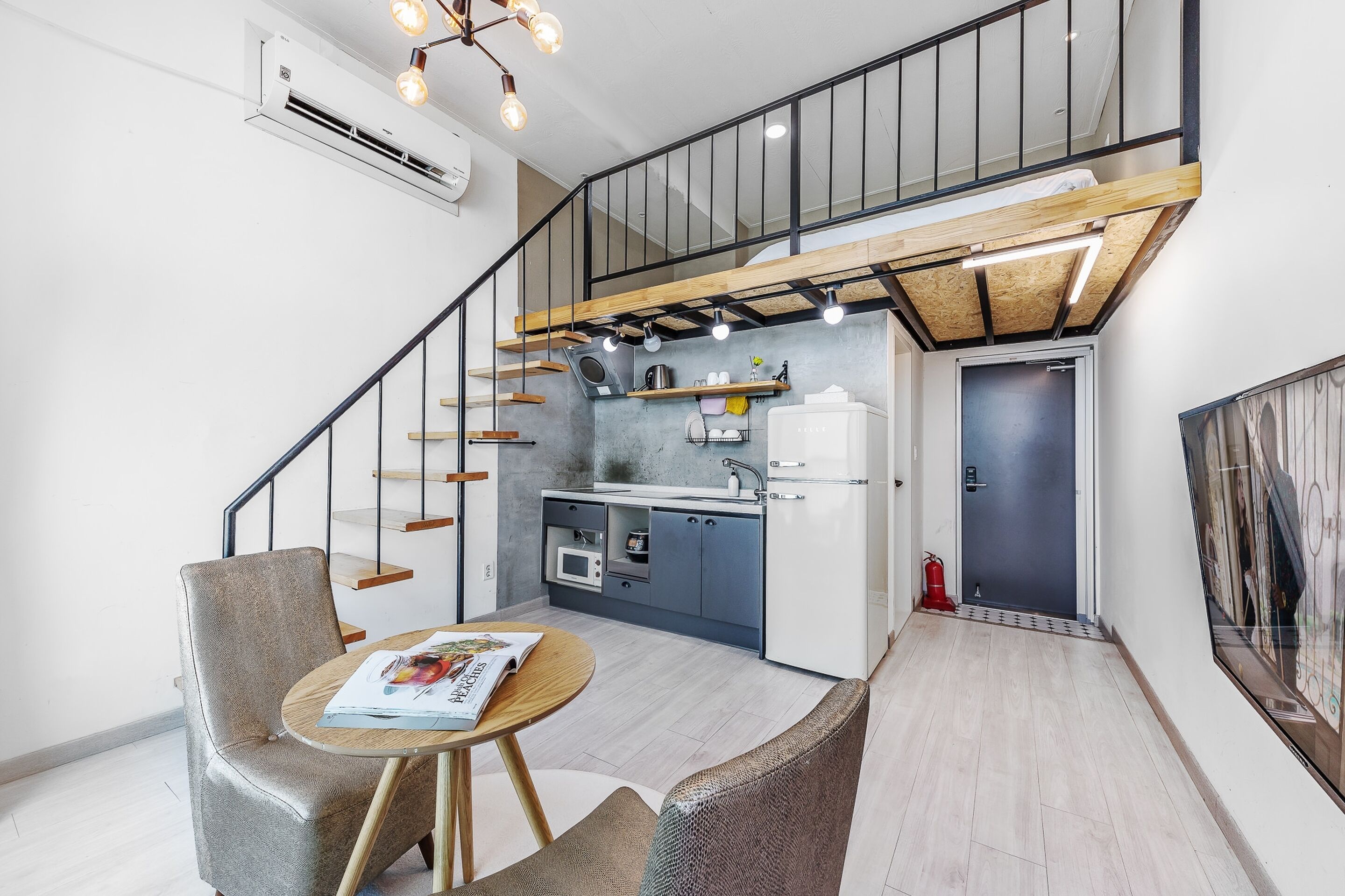 A modern apartment with a kitchen, dining area, and a staircase leading to a loft.