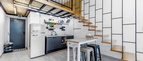 A modern kitchen with a built-in refrigerator, a coffee machine, and a wooden staircase.