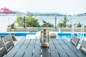 A wooden table with a lantern in the center, overlooking a swimming pool with lounge chairs and umbrellas. - Yeosu Lastella Spa Pet-friendly Pension (Yeosu)