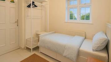 A bedroom with a bed, a bedside table, a wardrobe, a window, and a radiator.