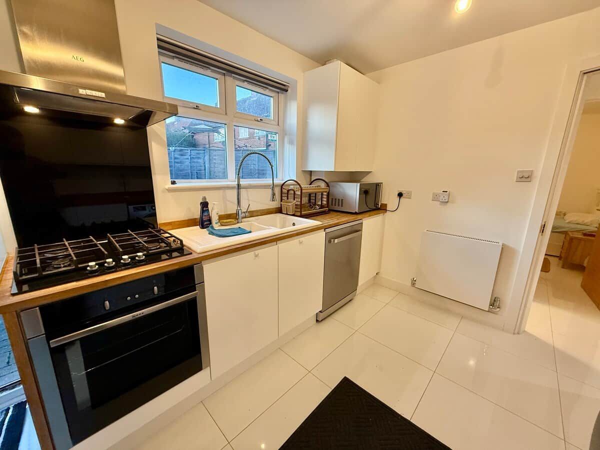 A modern kitchen with a gas stove, dishwasher, and white cabinetry.
