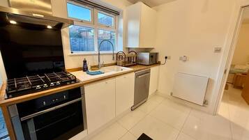 A modern kitchen with a gas stove, dishwasher, and white cabinetry.