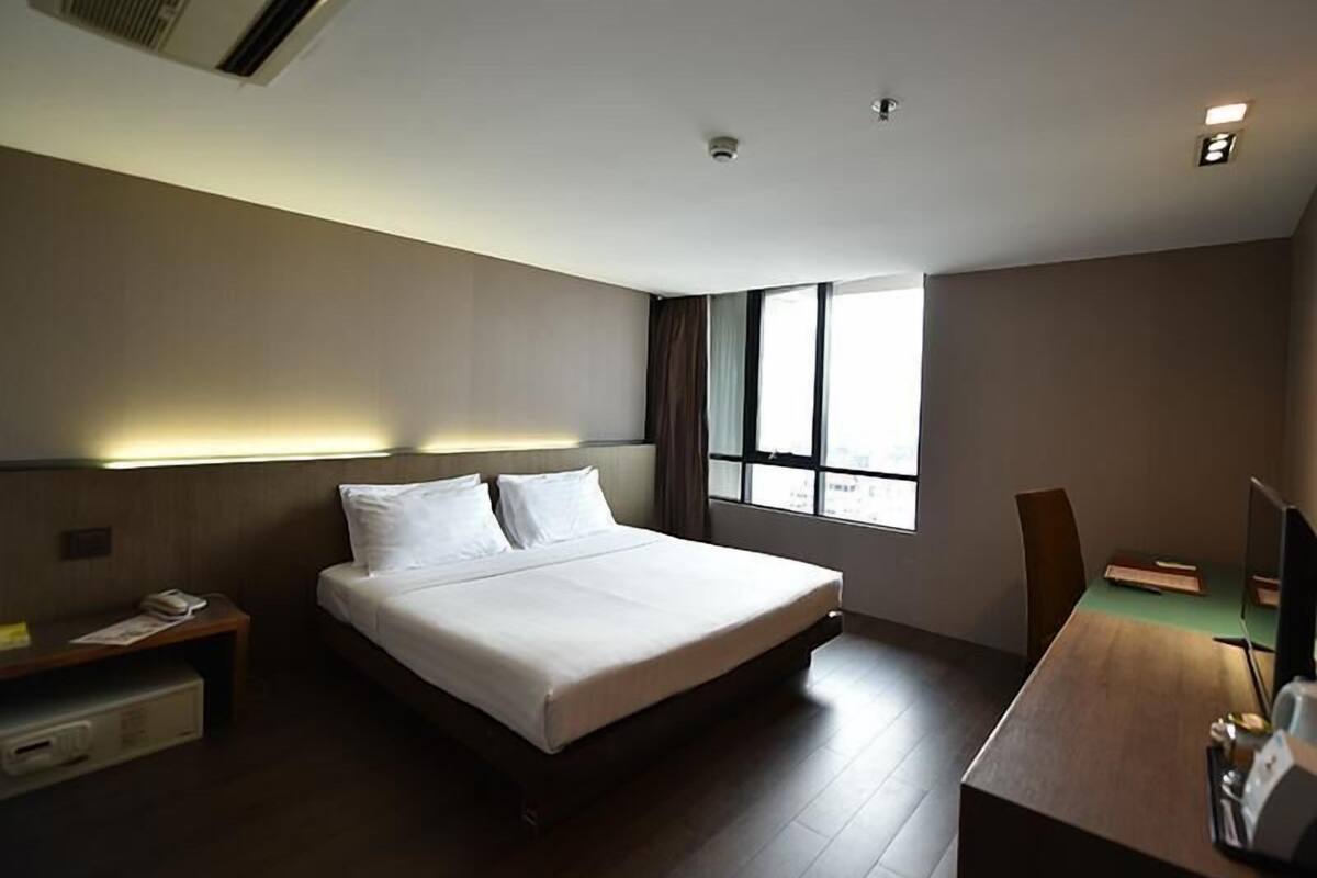 Een moderne hotelkamer met een groot bed, een bureau en een raam dat voor natuurlijk licht zorgt.