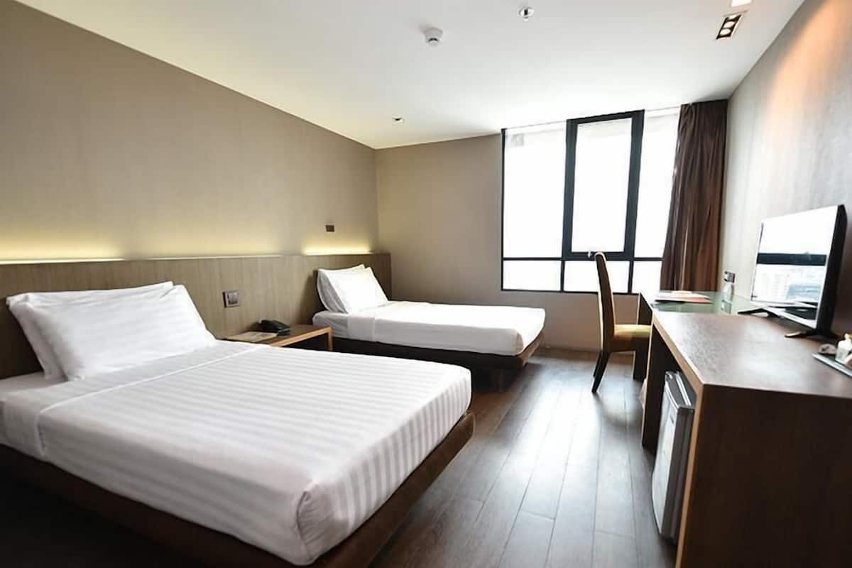 Een hotelkamer met twee bedden, een bureau, een stoel en een groot raam.