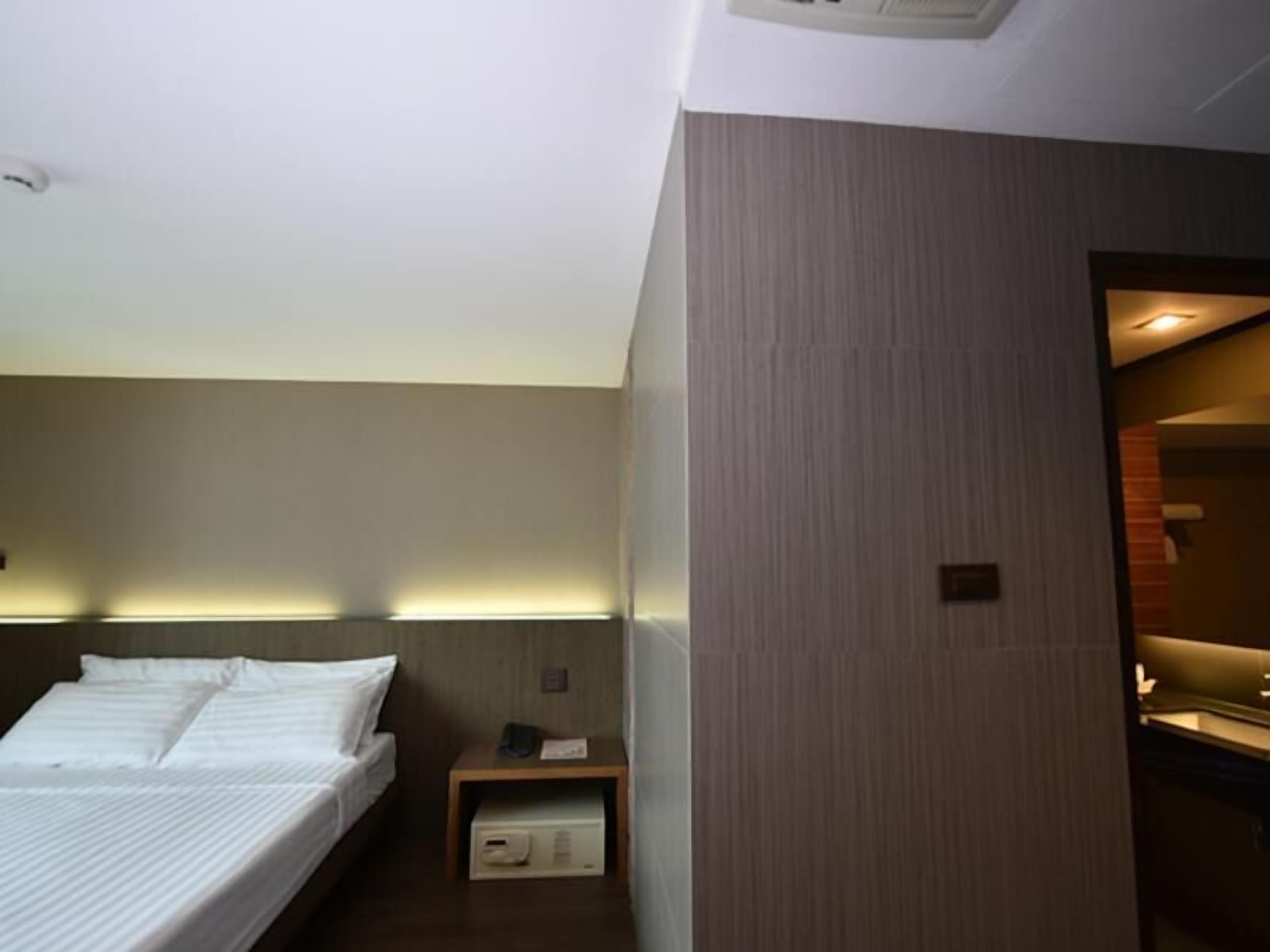 A hotel room with a bed, bedside table, and a small cabinet.