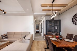 A modern living room with a sofa, a dining table with chairs, and a kitchen area with a cabinet. - Seaview Apartment Kostrena Two (Kostrena)