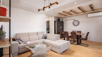 A modern living room with a sectional sofa, a glass coffee table, and a dining area with a wooden table and chairs.